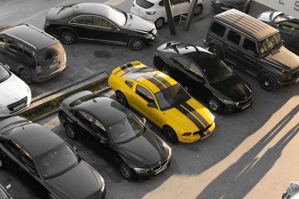 pexels-photo-15072149-15072149 Top view of various cars parked in a parking lot, featuring a yellow sports car.